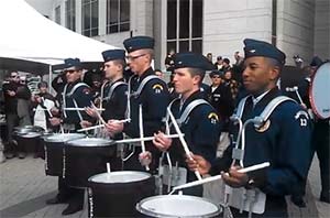 A line of five Air Force officers in navy blue uniforms play the drums.
