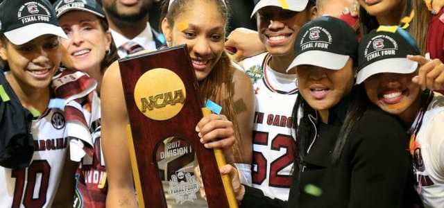 A girl holding an NCAA Division-I Final Four trophy from 2017 smiles, surrounded by her teammates.