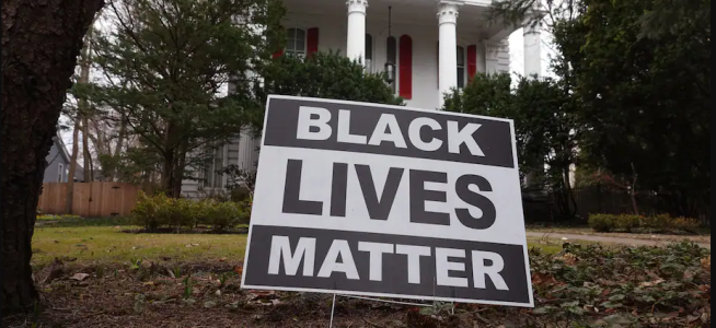 Black Lives Matter lawn sign in the front yard of a large white house.